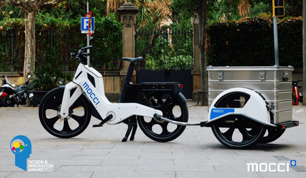 mocci Smart Pedal Vehicle with cargo trailer parked in an urban setting, winner of the 2023 Design & Innovation Award.